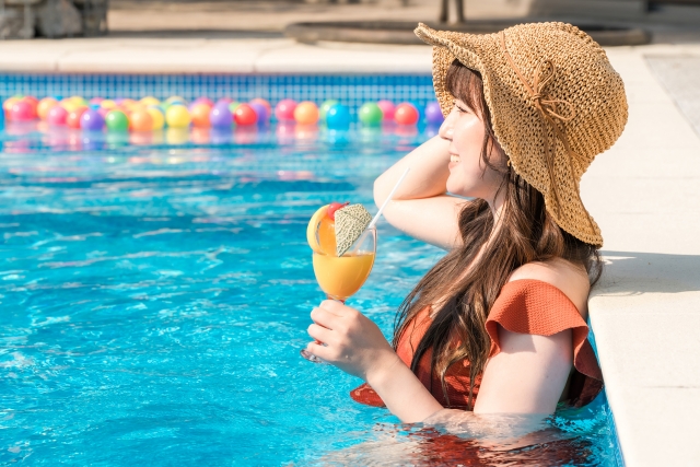 写真素材：リゾート地のプールでドリンクを飲む女性の画像